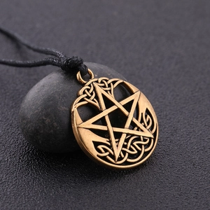 Macro shot of bronze pentagram necklace with Celtic knot patterns on a dark pebble