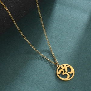 Close-up of golden Om symbol pendant with intricate hollow design on a fine chain