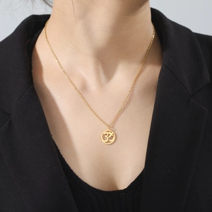 Primer plano de collar con colgante Om dorado en acero inoxidable usado con blazer negro