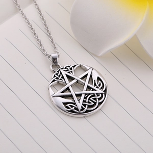 Close-up of vintage pentagram pendant with Celtic knot details on a notebook background