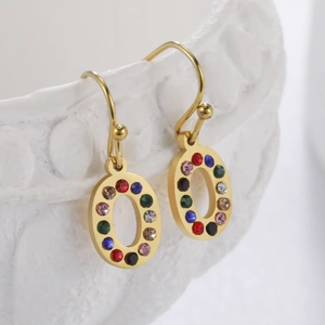 Gros plan détaillé de boucles d'oreilles ovales dorées avec strass colorés sur bol en porcelaine