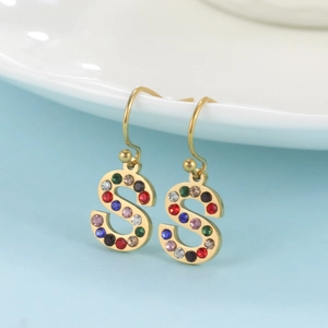 Gros plan de boucles d'oreilles lettre S dorées avec strass multicolores sur assiette