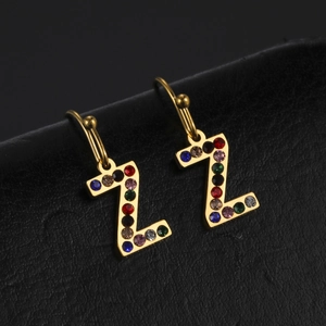 Gros plan d'une boucle d'oreille lettre Z dorée avec strass colorés sur cuir noir