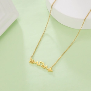 Macro detail of golden heart arrow and heartbeat pendant on stainless steel necklace