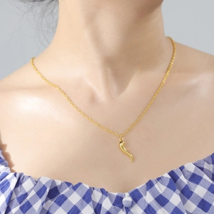 Detail of a minimalist gold Italian Horn pendant necklace worn on a model's neck