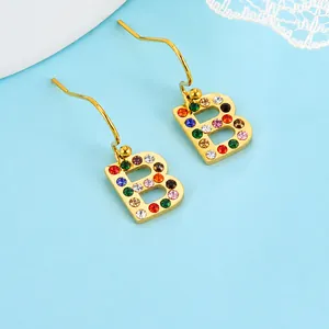 Boucles d'oreilles lettre B dorées style hip hop avec strass colorés sur fond bleu