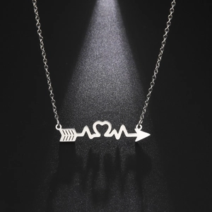 Macro shot of stainless steel heartbeat arrow necklace with heart detail on black background