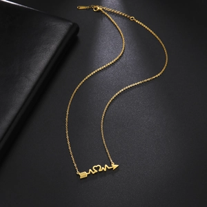 Macro view of gold MOM necklace pendant with arrow and heartbeat line design on black background
