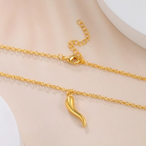Macro detail of golden cornicello pendant necklace with adjustable chain on silk background