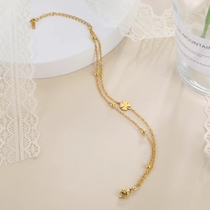 Detail of a double-layered gold four-leaf clover bracelet on a display stand