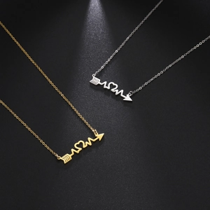 Minimalist heart arrow EKG necklace in gold and silver finish on a black background
