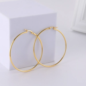 Detailed view of large gold polished hoop earrings on white geometric minimalist display