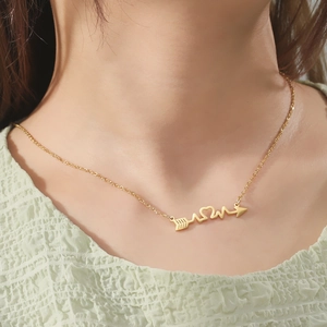 Gold stainless steel heartbeat and arrow heart pendant necklace worn by model