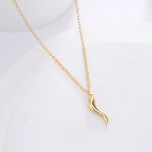 Detailed view of a polished golden cornicello horn pendant on a delicate chain necklace
