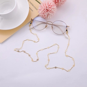Détail de la chaîne à lunettes en métal doré avec pendentifs roses évidées et boucles silicone