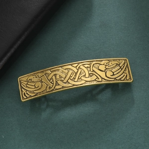 Vintage gold rectangular hair clip featuring celtic knots and bird patterns on green backdrop