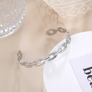 Detailed view of silver chain link open bangle with polished oval motifs on display