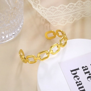 Close-up of gold-plated oval link chain bracelet on a decorative white surface