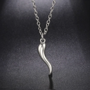 Macro detail of silver-colored cornicello horn pendant on a metal link chain necklace