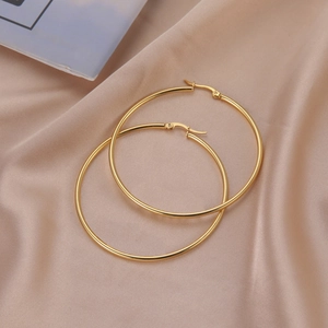 Chic gold geometric hoop earrings displayed on elegant champagne silk background