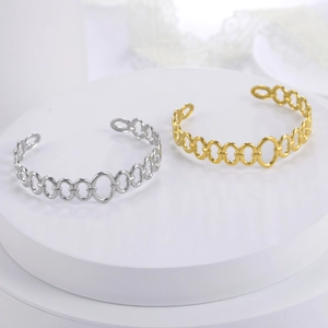 Detail of gold and silver plated cutout link chain cuff bracelets on a white display