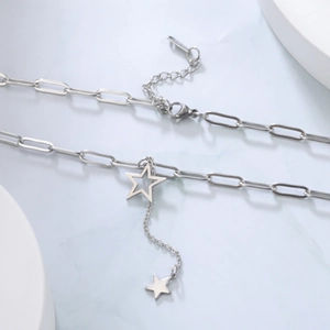 Detail view of silver paperclip chain necklace with hollow and solid star pendants