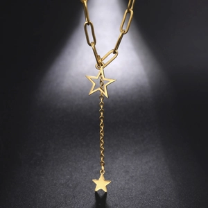 Detail of gold Y-shaped necklace featuring hollow and solid star pendants on paperclip chain