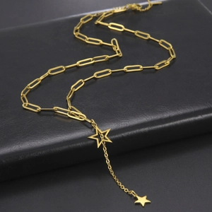 Detail of golden paperclip chain necklace with hollow and solid double star pendants