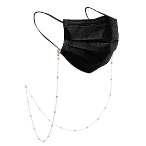 Detail van 18K vergulde kralenketting met karabijnsluitingen op een zwart masker