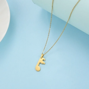 Macro shot of minimalist gold music note pendant with delicate polished chain