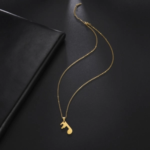 Detail of a gold music note pendant on a stainless steel chain over a dark background