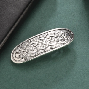 Vintage silver Celtic knot hair clip with intricate woven relief design on a dark surface