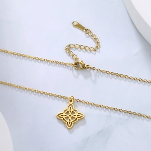 Détail du pendentif nœud celtique doré avec fermoir mousqueton sur marbre