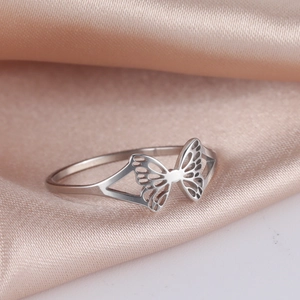 Elegante anillo de mariposa calado en acero inoxidable pulido sobre satén champán