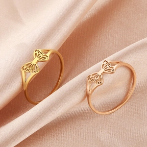 Anillos de mariposa calados en oro y oro rosa sobre un fondo de seda rosa