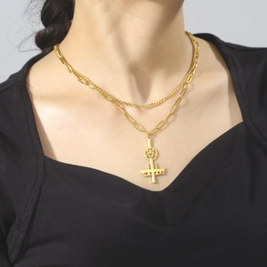 Close-up of golden double layer necklace with inverted cross and pentagram star pendant