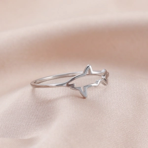 Detalle de anillo plateado con diseño de tiburón calado sobre tela de seda rosada