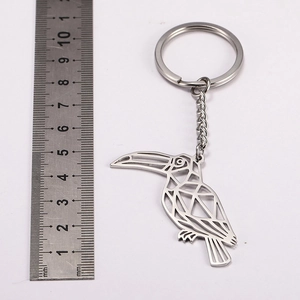 Stainless steel toucan keychain with hollow geometric design next to a measuring ruler