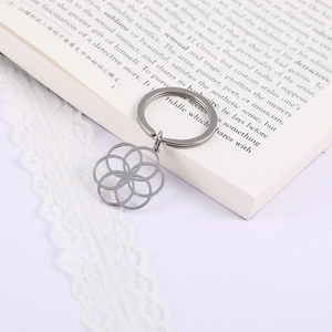 Portachiavi in acciaio inossidabile con ciondolo a fiore geometrico su libro aperto