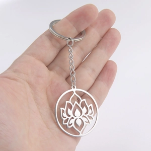 Close-up of silver hollow lotus pendant keychain in hand with polished steel finish