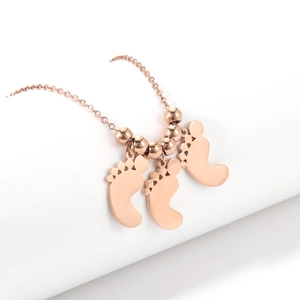 Dettaglio della collana in oro rosa 18K con tre ciondoli a forma di piedi e perle