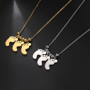 Dettaglio di ciondoli a forma di impronta in oro 18K e argento con perle lucide su catene