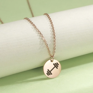 Detail view of rose gold barbell engraved round coin pendant on a delicate chain
