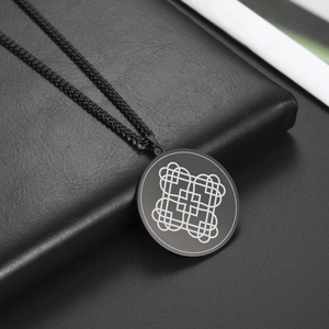 Dettaglio macro della collana con talismano nero circolare e motivo a cuore geometrico