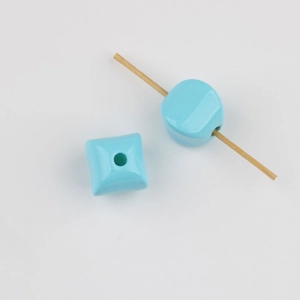Macro detail of sky blue acrylic square beads with large vertical holes on wooden sticks