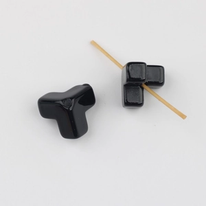 Close-up of black glossy T-shaped acrylic beads showing center hole for DIY jewelry