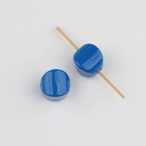 Close-up of blue glossy acrylic beads with vertical holes for DIY jewelry making