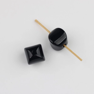 Macro detail of black glossy acrylic cube beads showing the vertical hole structure