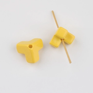 Detail of yellow Y-shaped acrylic bead with smooth finish and functional hole for DIY jewelry