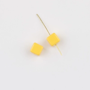 Close-up of bright yellow acrylic cube beads with straight holes for DIY jewelry crafting